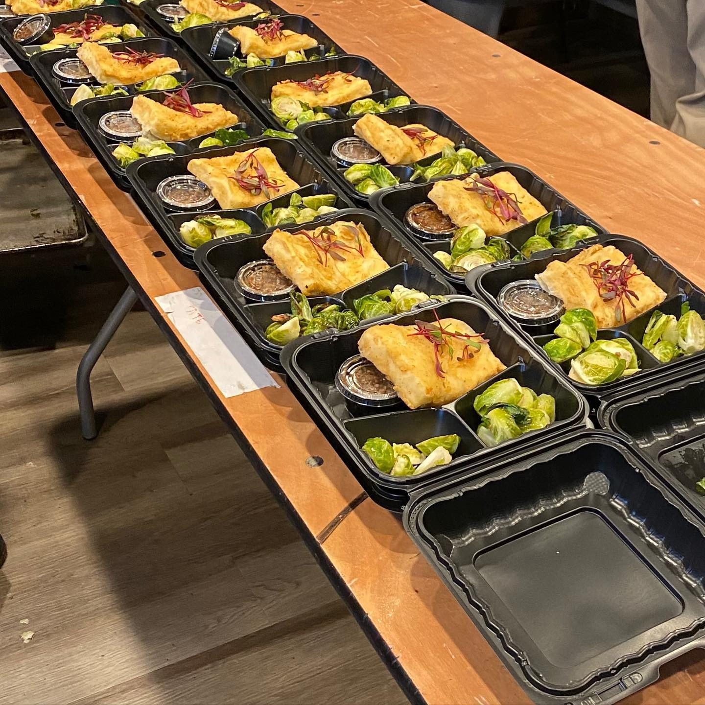Boxed lunches with crispy fish, roasted Brussels sprouts and sauce for a film crew
