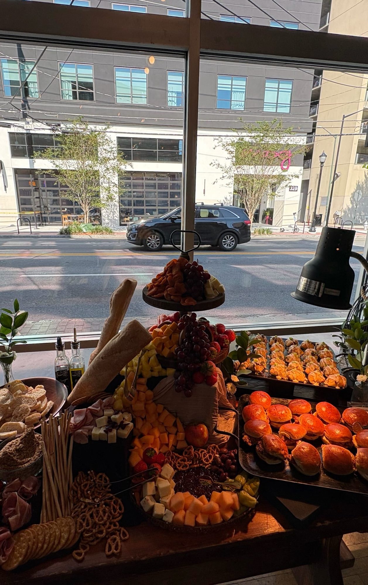 Grazing display with tiered fruit, charcuterie, baguettes and trays of sliders