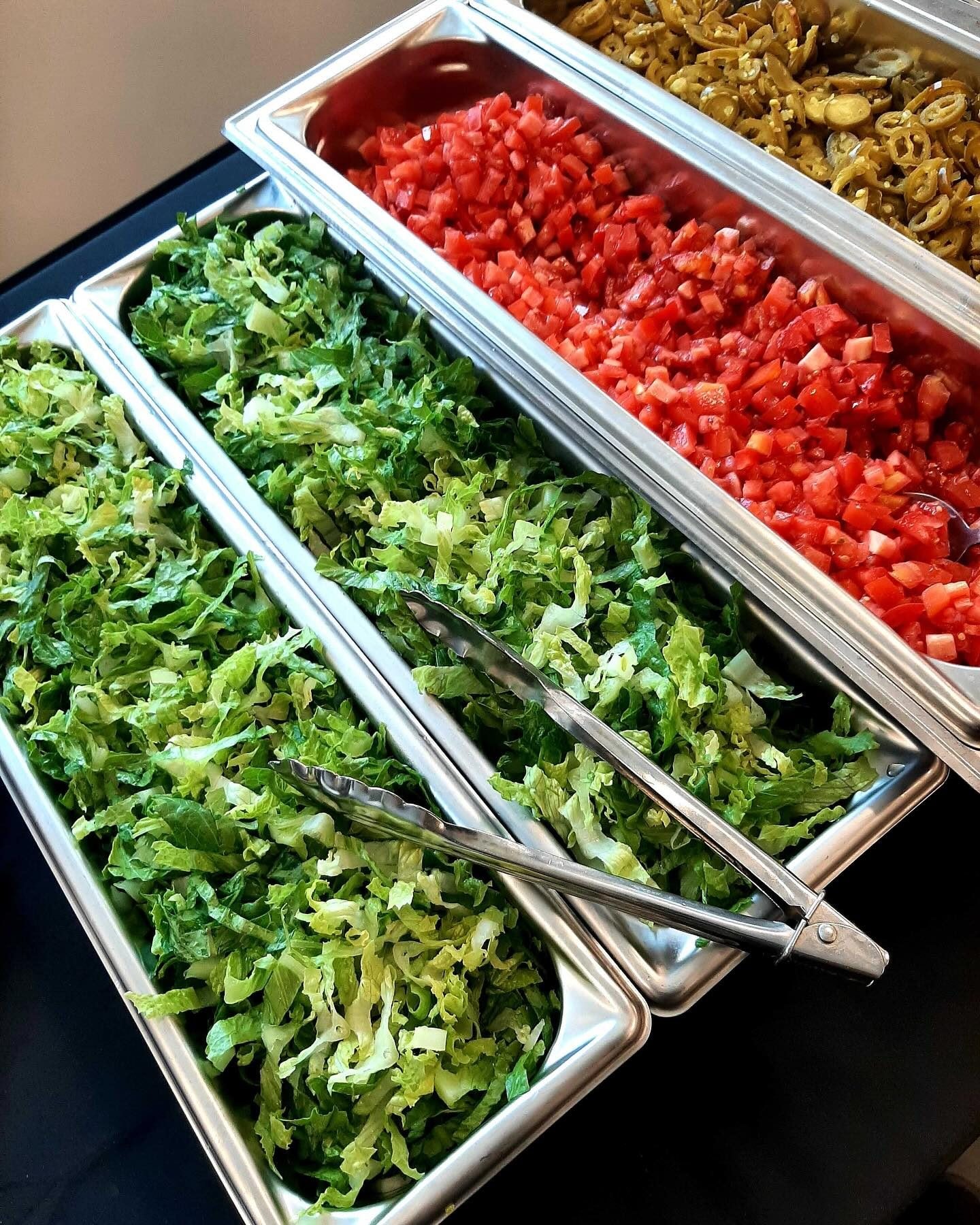 Taco bar toppings with shredded lettuce, diced tomatoes and jalapenos