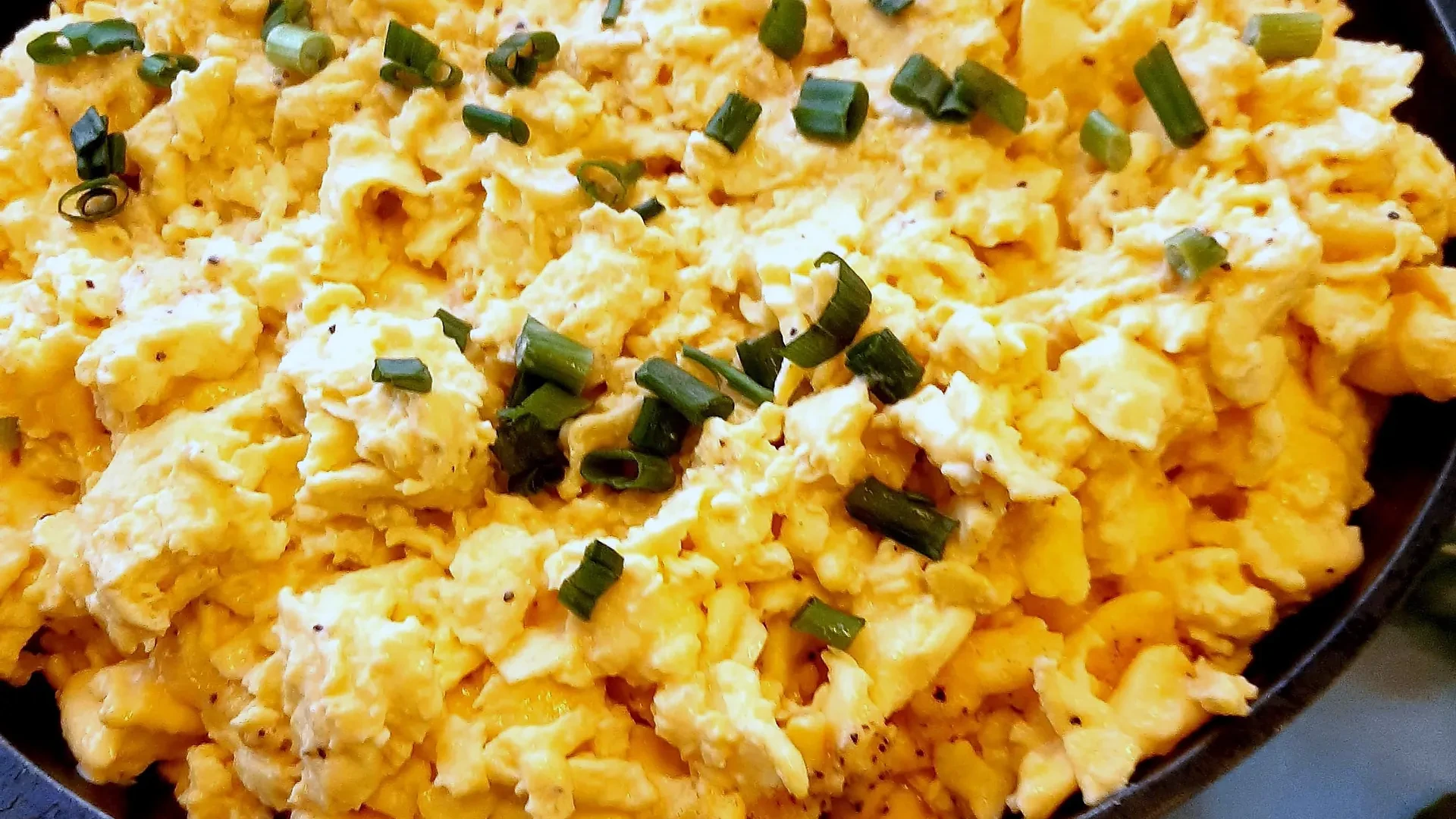 Cast-iron skillet of cheesy scrambled eggs with chives — Atlanta production catering breakfast service