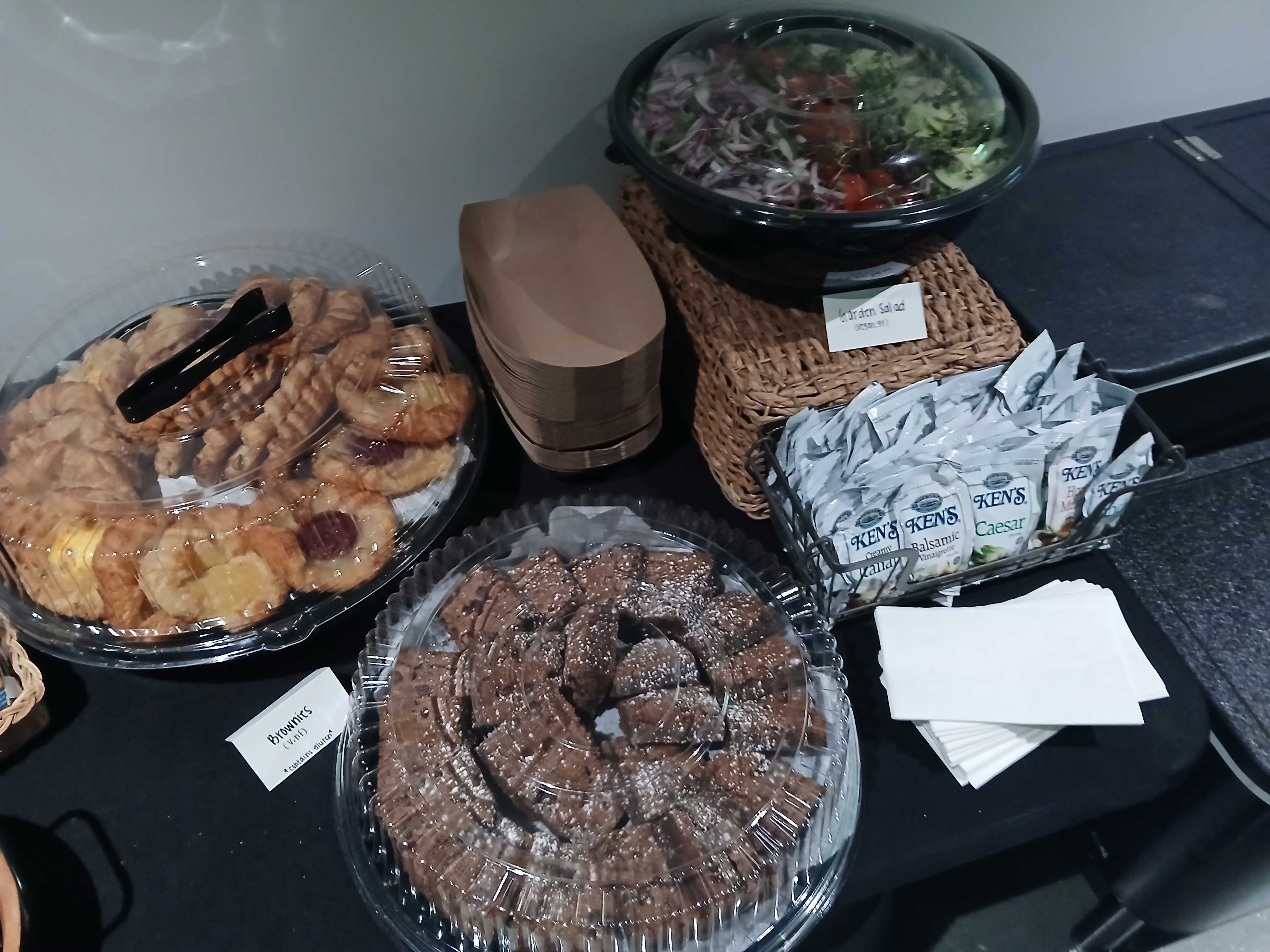 Atlanta production catering dessert and salad station — vegan brownies, assorted cookies, garden salad in a bowl, and Ken's Italian, Balsamic, and Caesar dressing packets