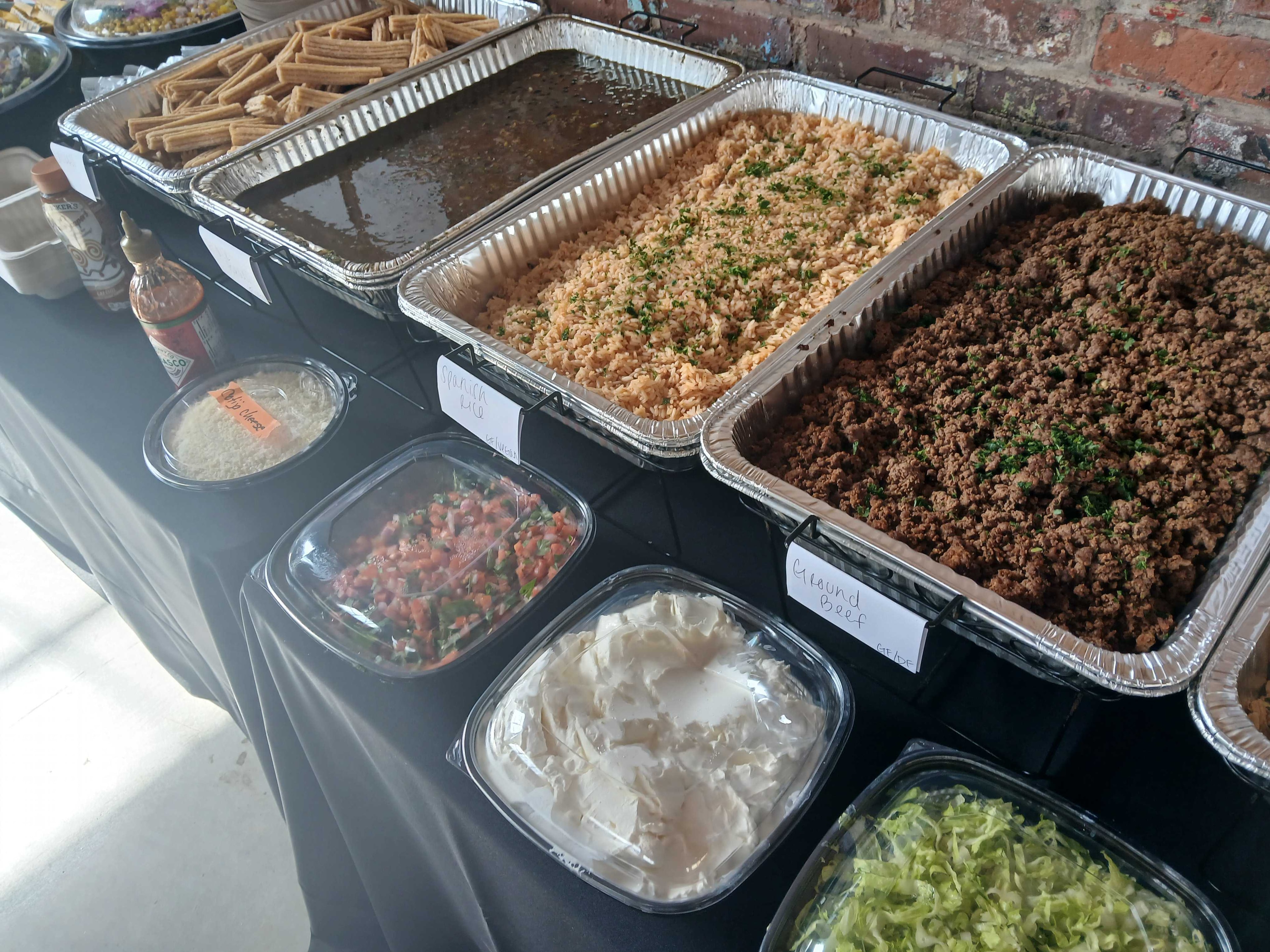 Taco bar spread with Spanish rice, seasoned ground beef, pico de gallo, sour cream, and toppings — Atlanta production catering