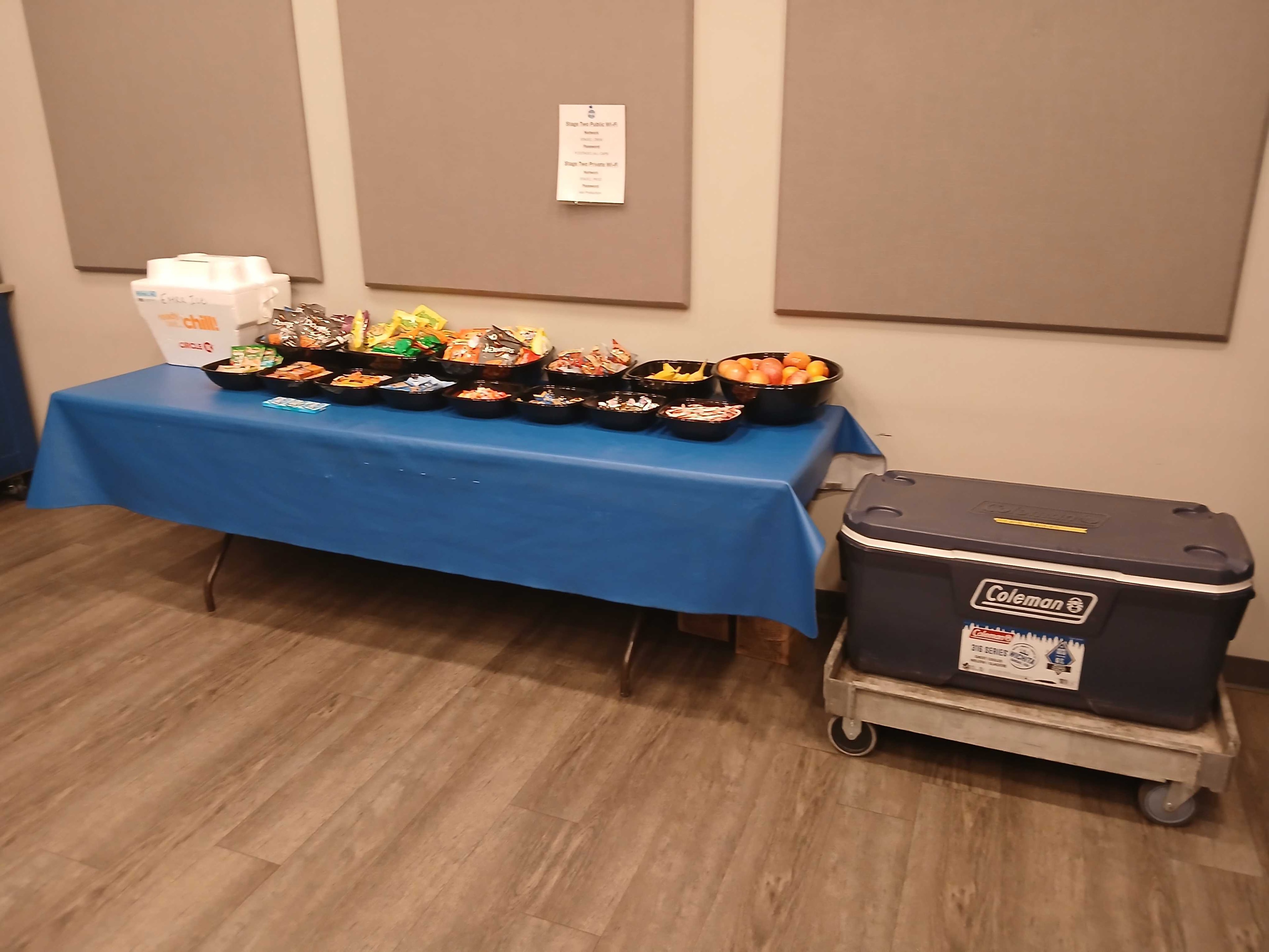 Craft service table with individual snack bowls, candy, and a cooler on a blue tablecloth — Atlanta film production