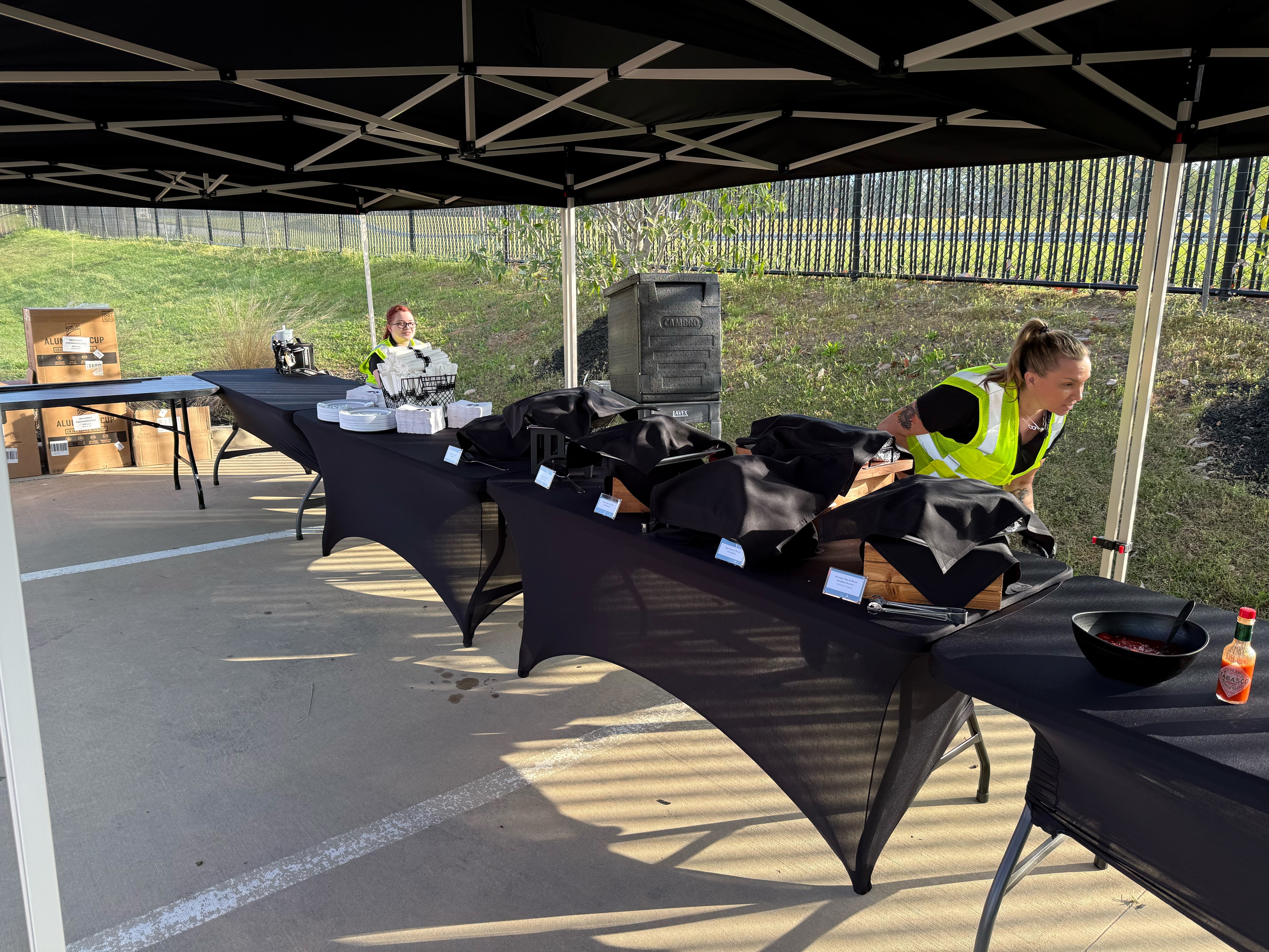 Atlanta Craft Services staff preparing food tables under black branded catering tents at a Cummins outdoor corporate event