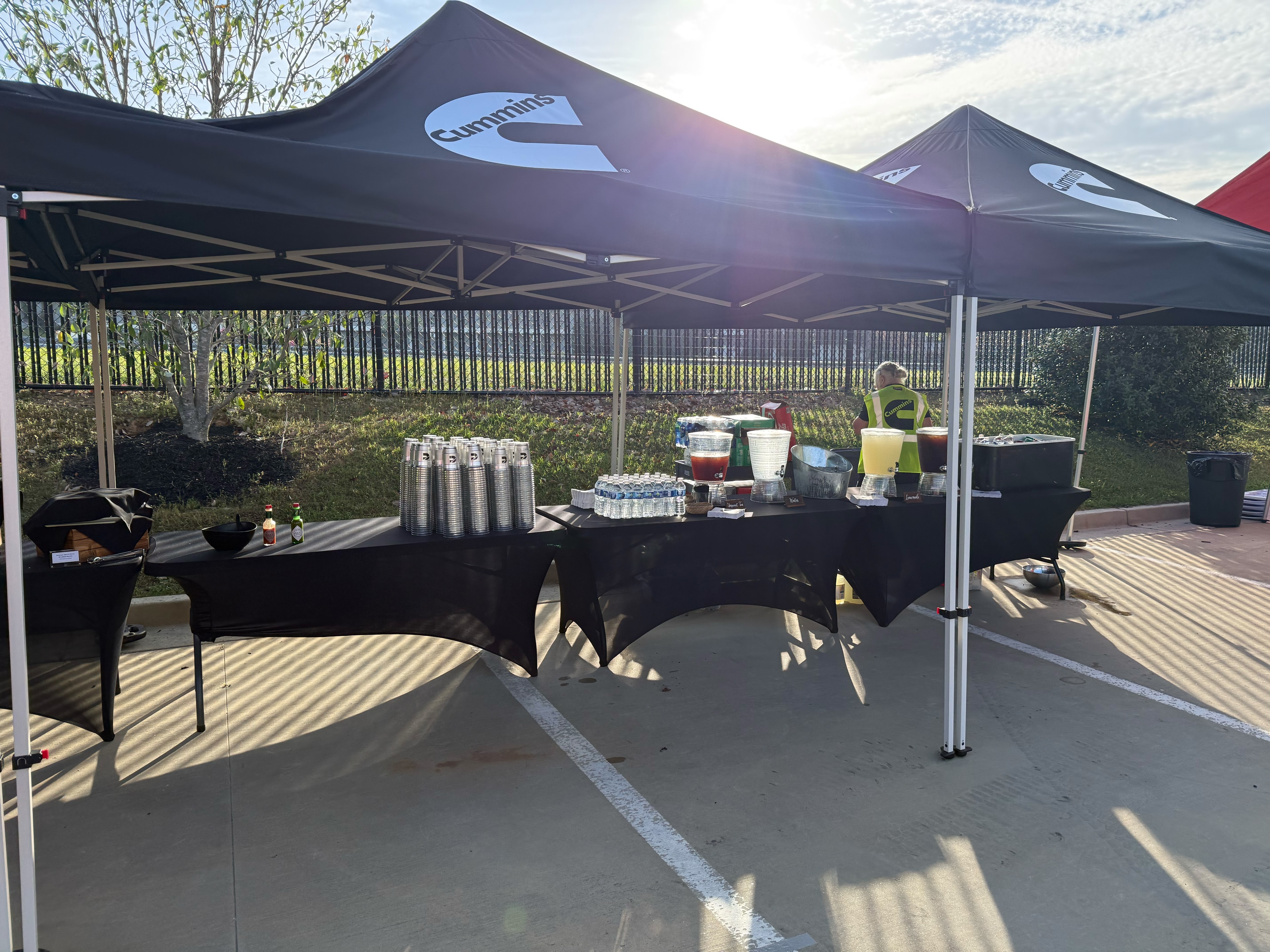 Catering staff in safety vests arranging food service tables under black tents at a Cummins corporate event in Atlanta