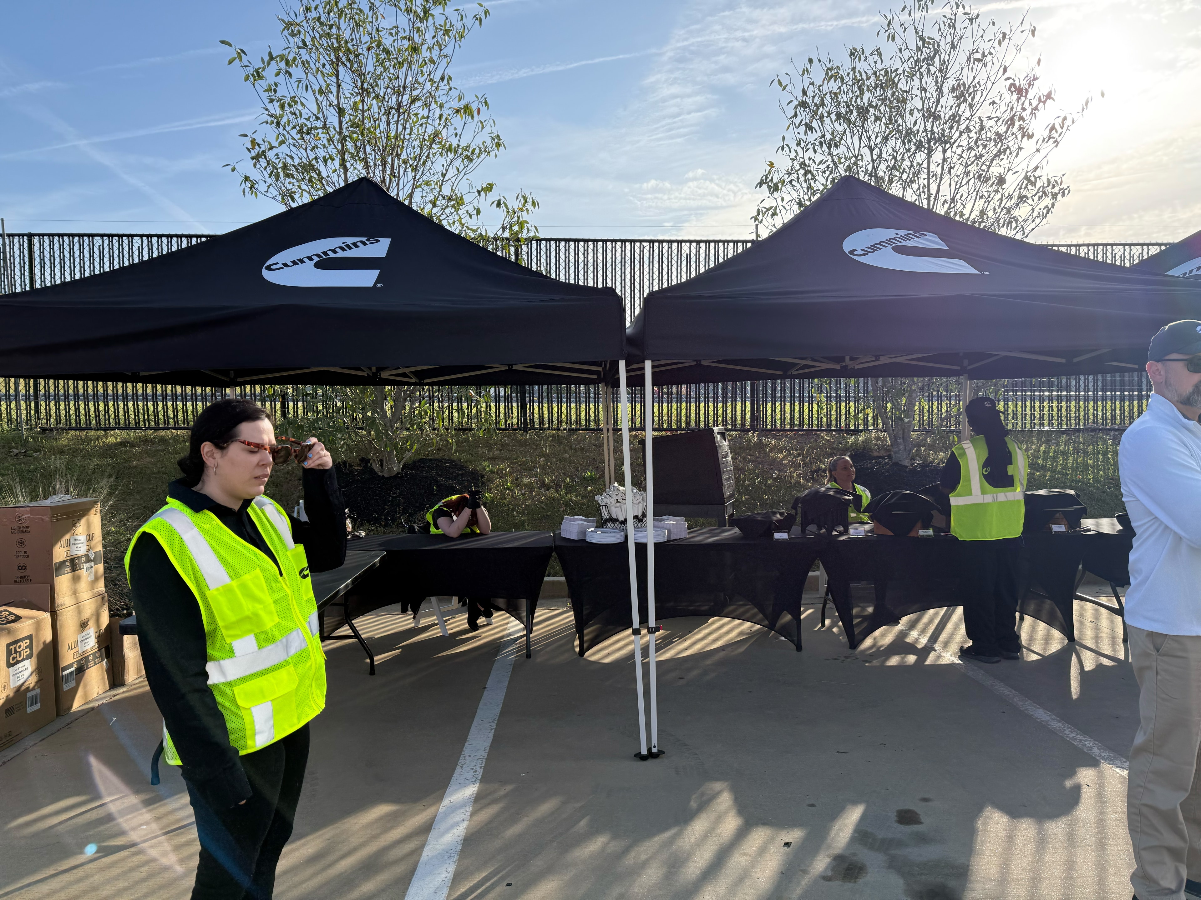 Atlanta Craft Services staff in safety vests setting up black catering tents at a Cummins corporate outdoor event