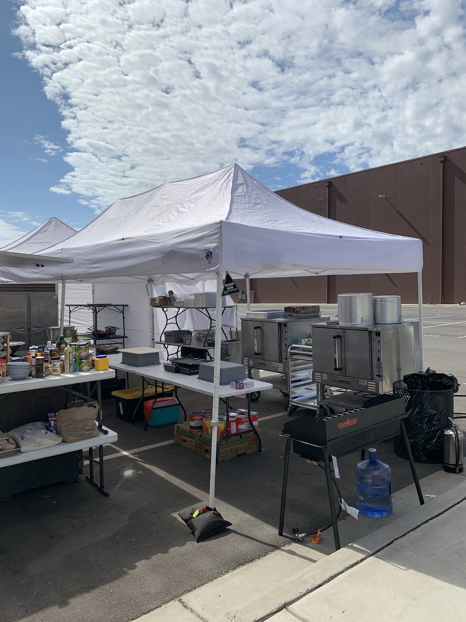 Outdoor production catering kitchen setup under a white tent with commercial ovens, prep tables, and cooking equipment — Atlanta film set catering