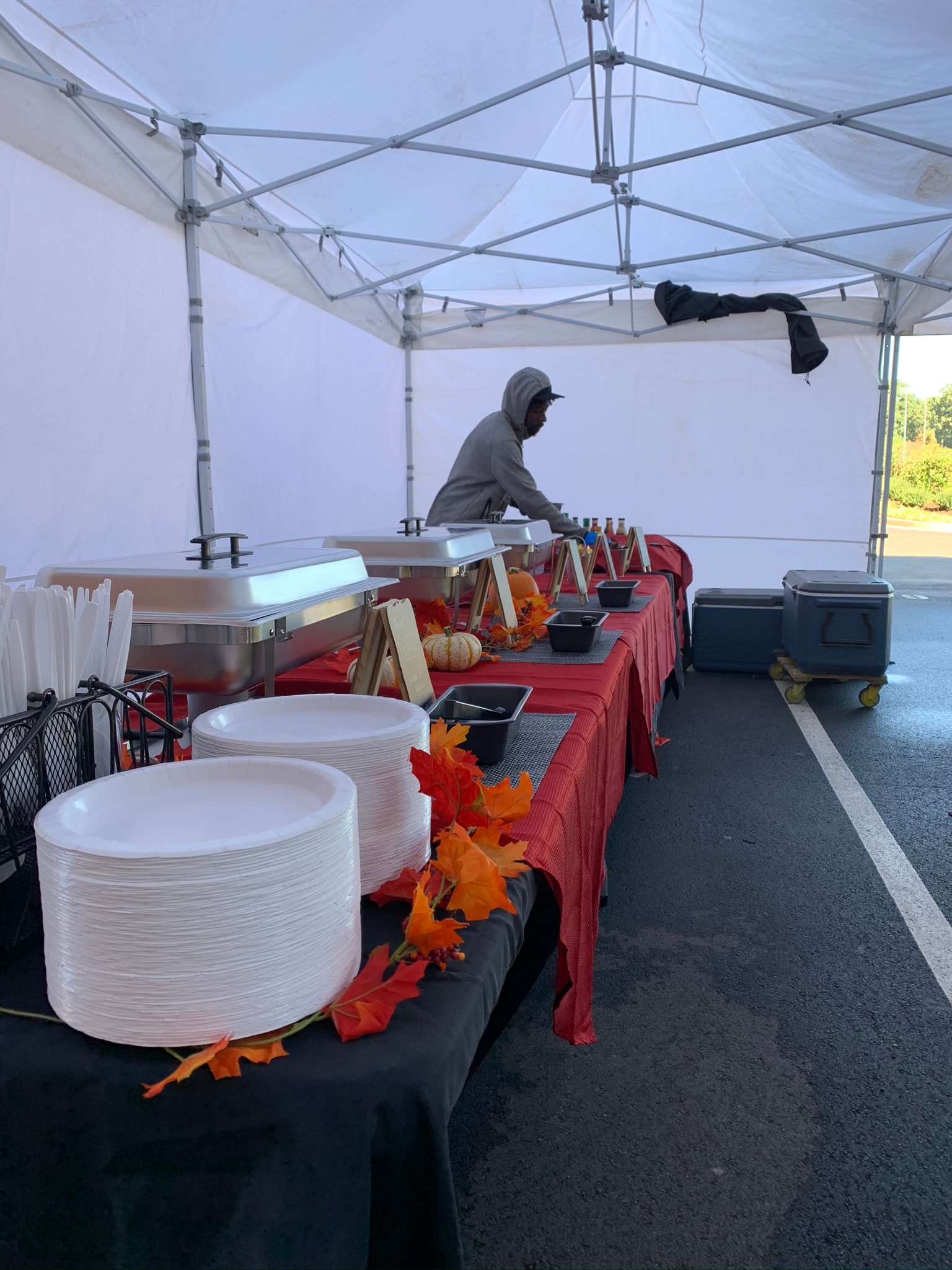 Atlanta Craft Services catering staff setting up a buffet under a white tent with fall decorations — pumpkins, autumn leaves, red tablecloths, and chafing dishes