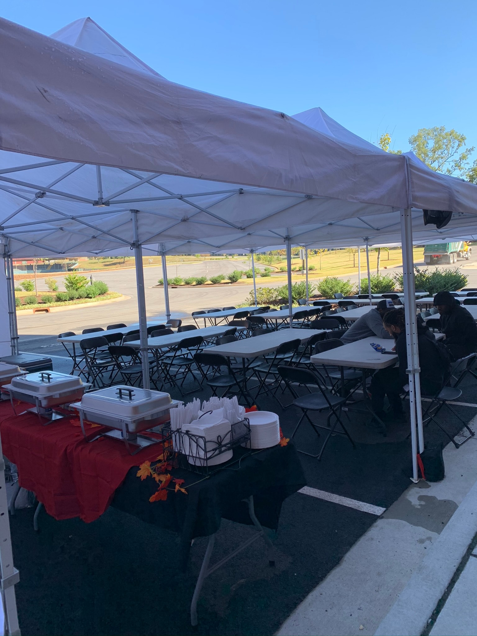 Wide outdoor tent setup with rows of folding tables and chairs ready for a large catered meal — Atlanta film production catering